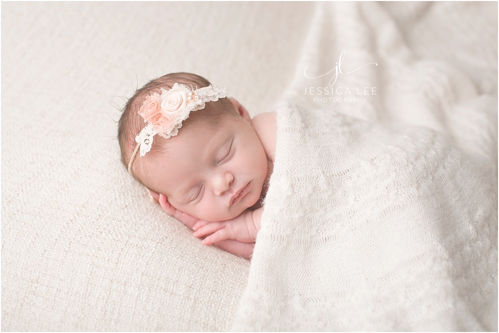 Baby Photographer Erie, newborn cuddling in white blanket