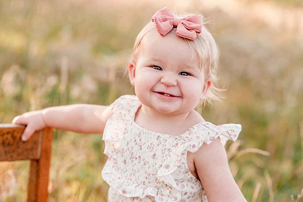 Toddler girl in floral jumper smiling at the camera | Photo by Jessica Lee Photography