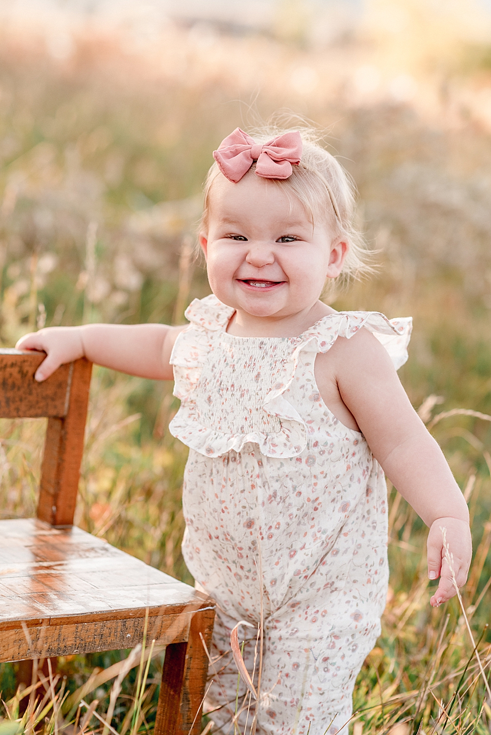 Toddler girl in pink bow smiling at the camera | Photo by Jessica Lee Photography
