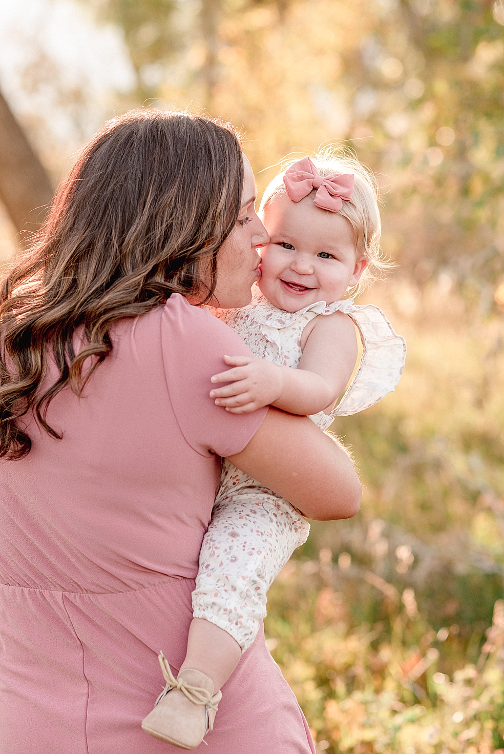 Mom in pink dress giving toddler baby a kiss | Photo by Jessica Lee Photography