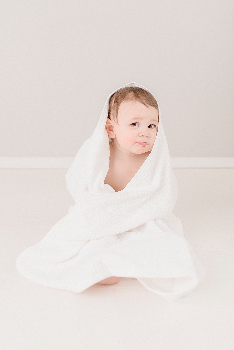 Baby boy in white towel making faces at the camera | Photo by Jessica Lee Photography