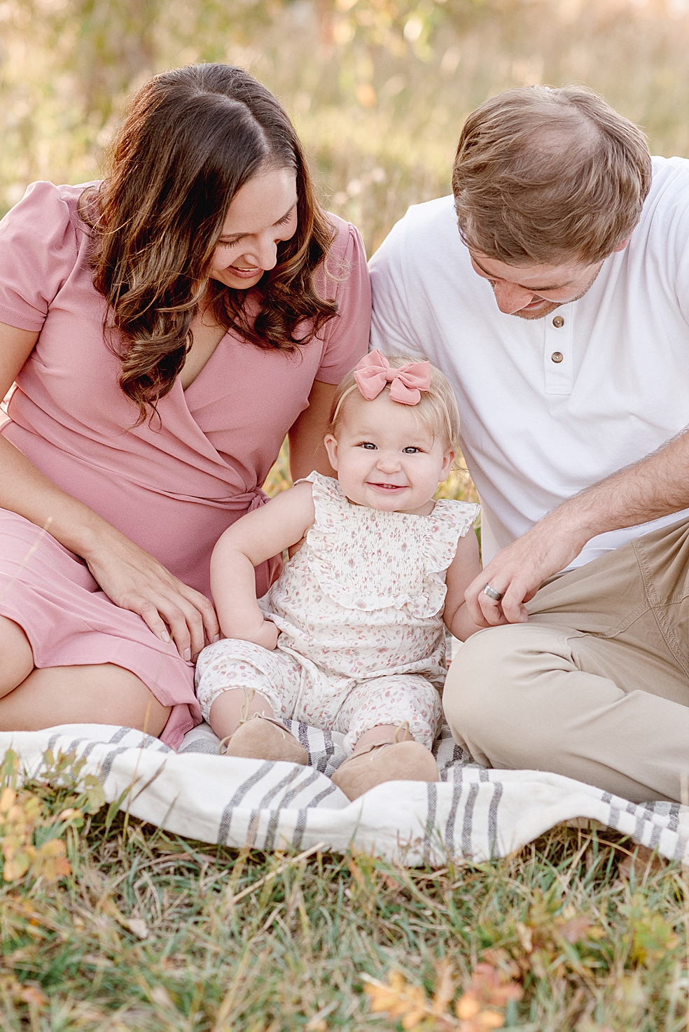 Mom dad and baby girl sitting on a blanket in the grass | Photo by Jessica Lee Photography