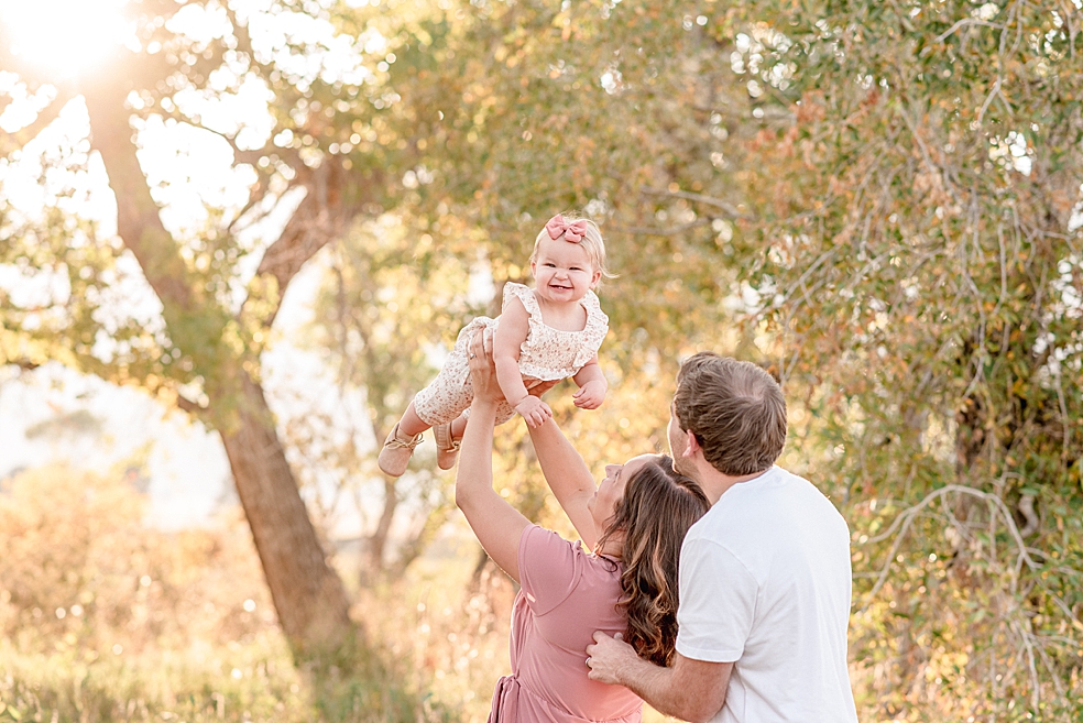 Mom and dad playing with toddler baby girl in a field | Photo by Jessica Lee Photography