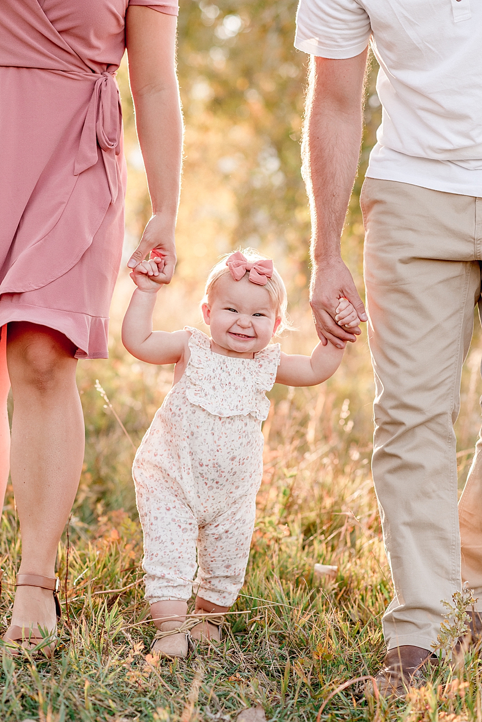 Toddler girl walking in a field with mom and dad | Photo by Jessica Lee Photography