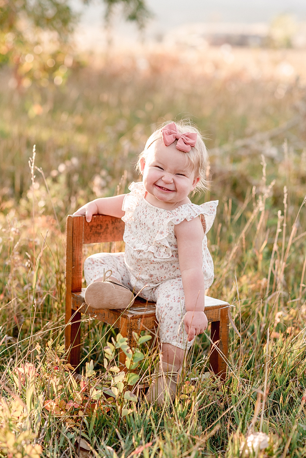 Baby girl in floral jumper scrunching nose and smiling at the camera | Photo by Jessica Lee Photography
