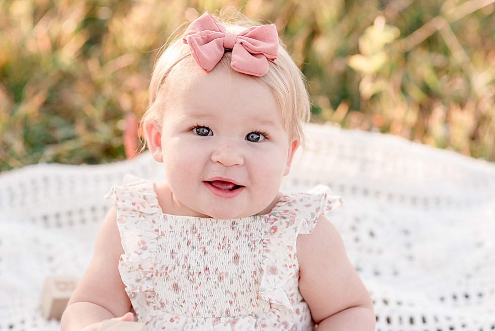 Toddler baby girl with pink bow looking at the camera | Photo by Jessica Lee Photography