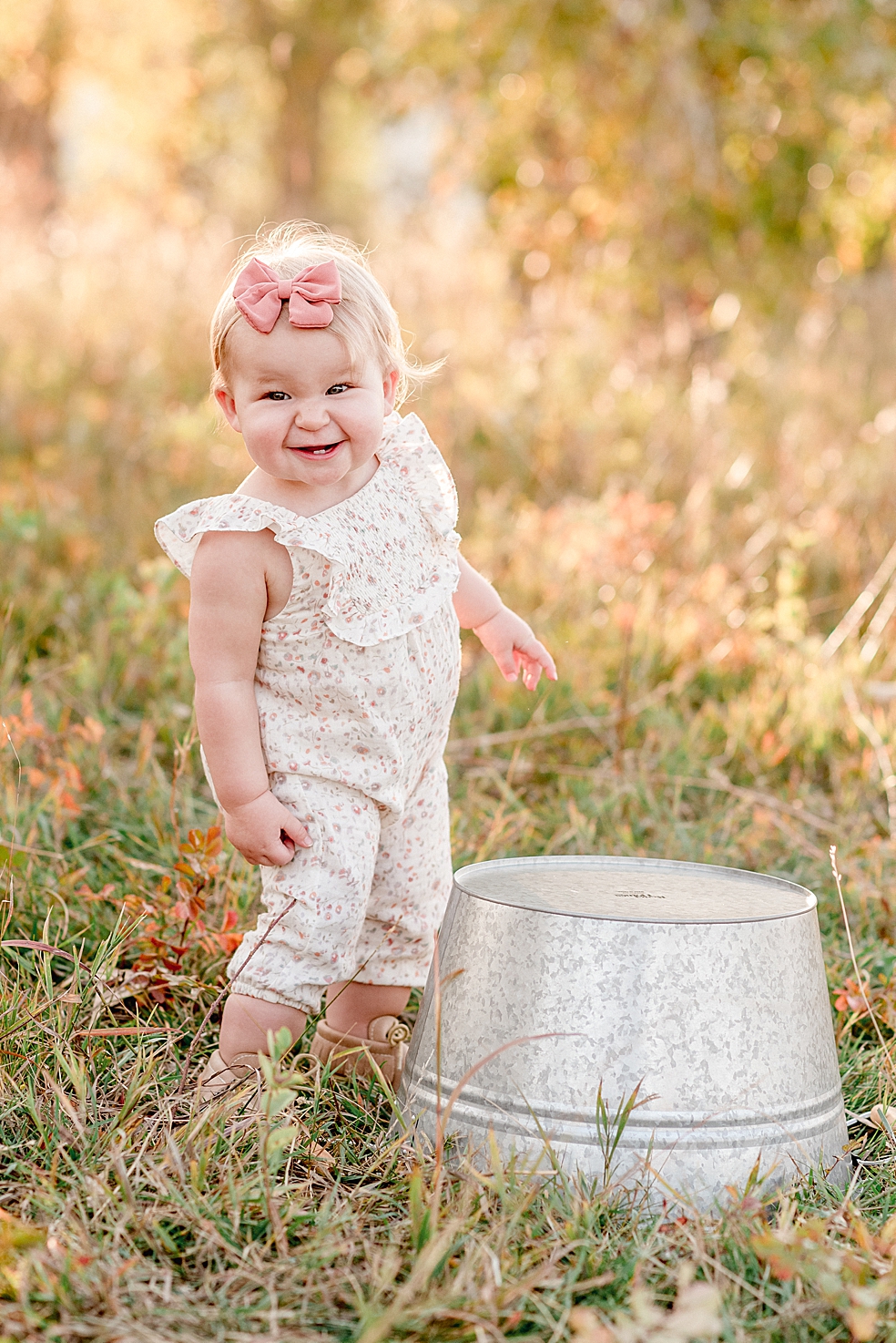 Baby girl in floral jumper and pink bow looking at the camera | Photo by Jessica Lee Photography