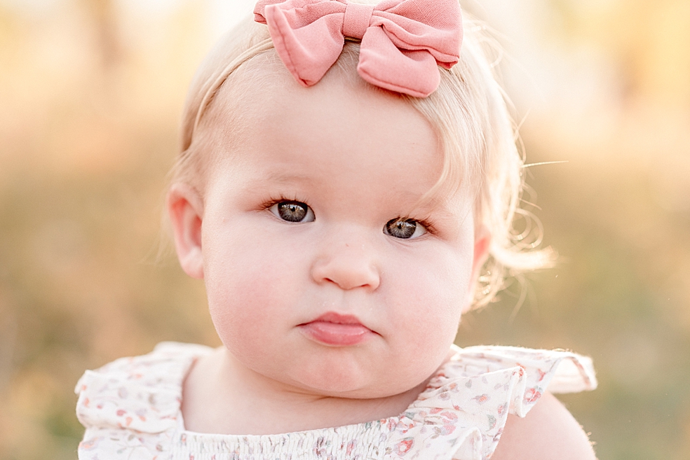 Baby girl with pink bow in floral jumper | Photo by Jessica Lee Photography