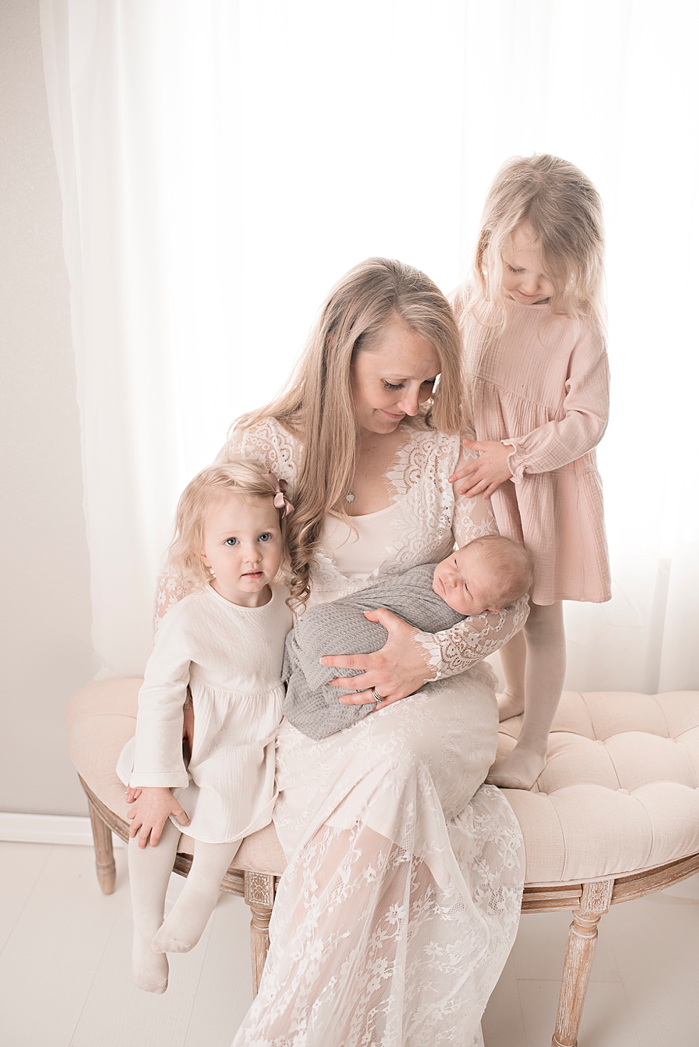 Mom and two daughters admiring newborn baby boy | Photo by Jessica Lee Photography