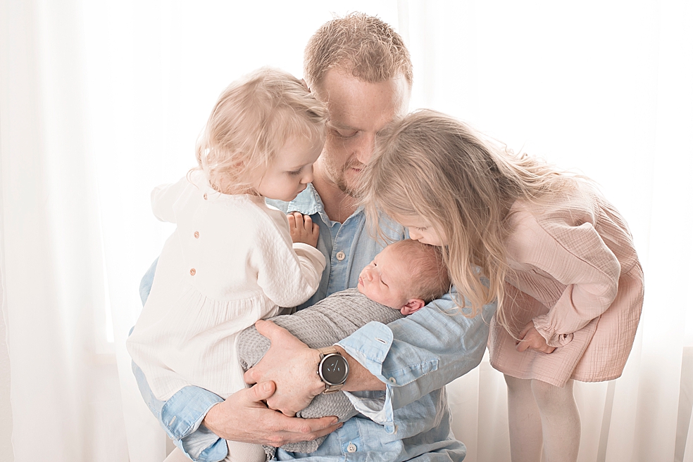 Dad holding his toddler daughters and newborn baby boy | Photo by Jessica Lee Photography