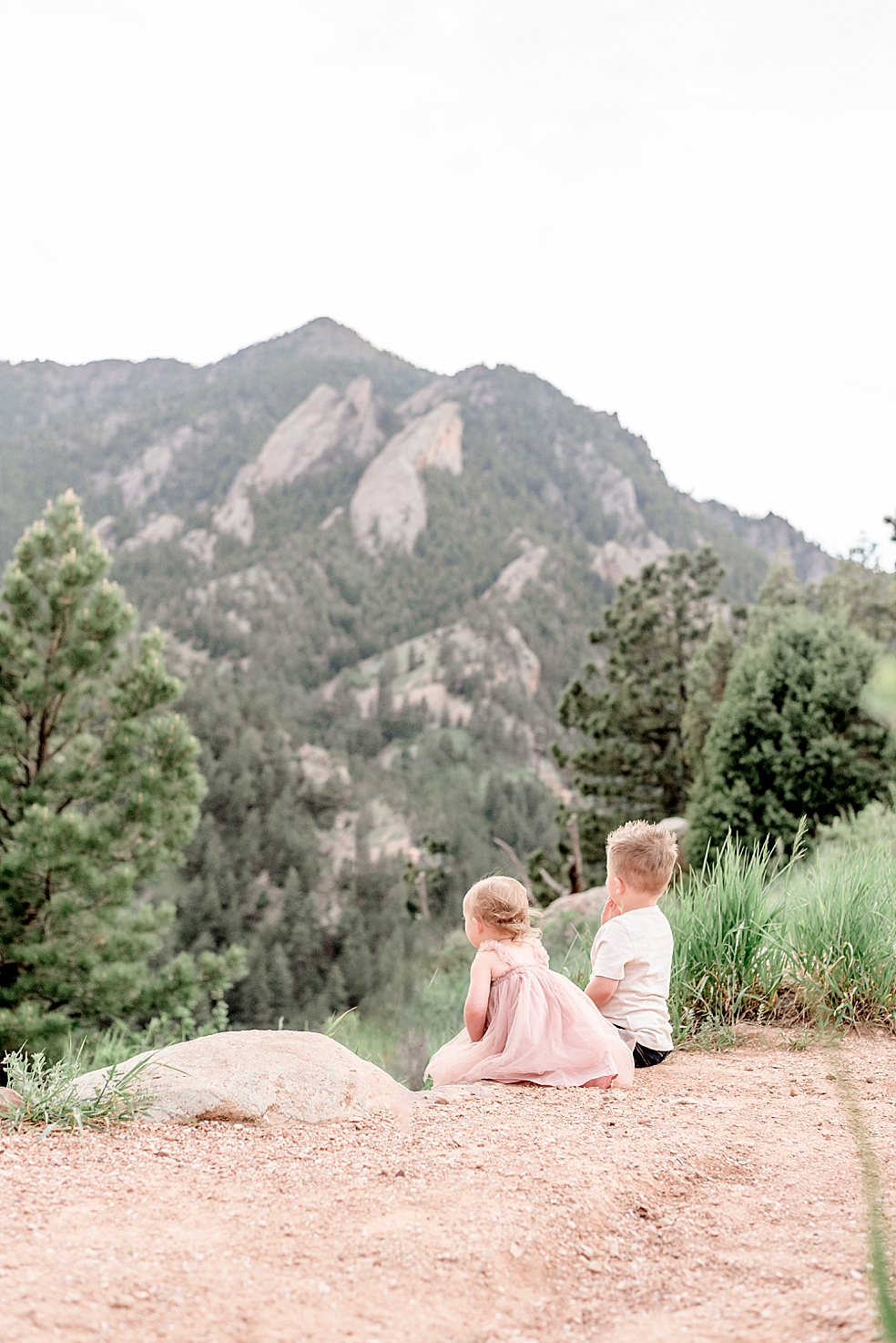Brother and little sister sitting on the ground looking at mountains | Photo by Jessica Lee Photography