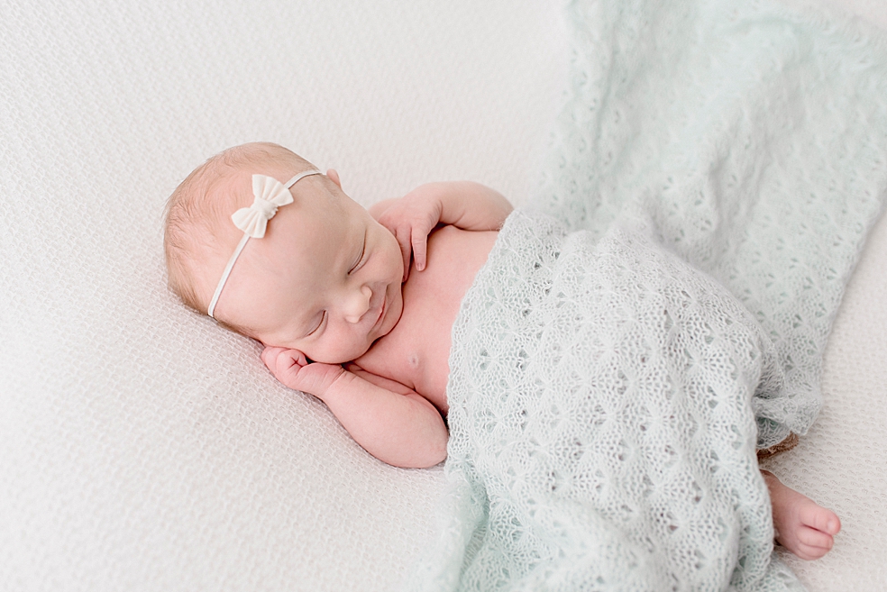 Sleeping baby girl in pale blue swaddle and bow | Photo by Jessica Lee Photography