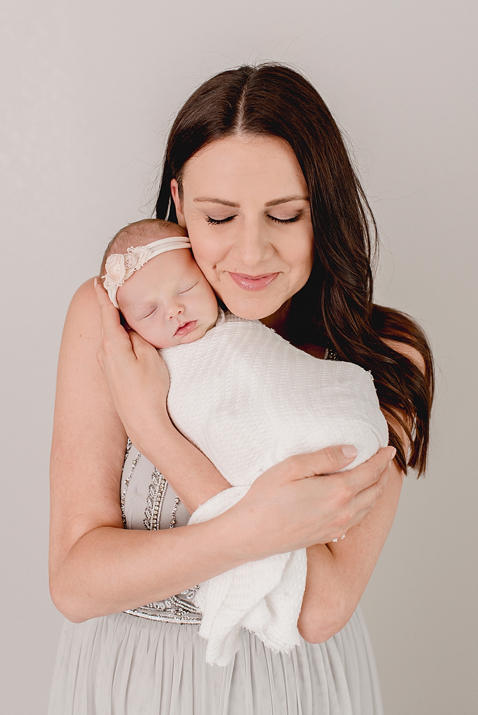 Mom snuggling newborn baby girl in headband | Photo by Jessica Lee Photography