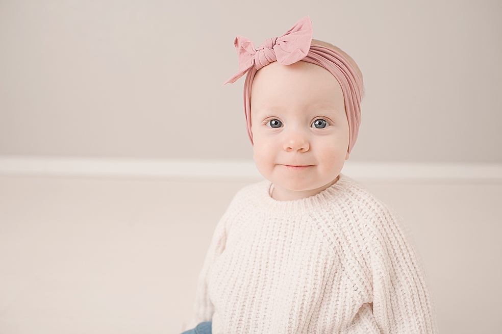 Smiling baby girl with a pink bow | Photo by Jessica Lee Photography 