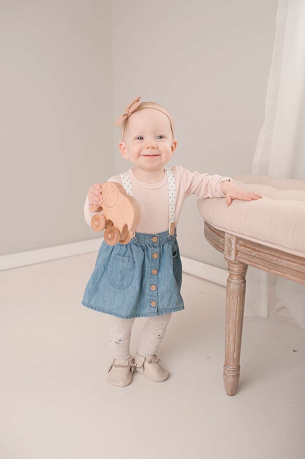 Toddler girl standing and holding a wooden elephant | Photo by Decatur Alabama Baby Photographer Jessica Lee 