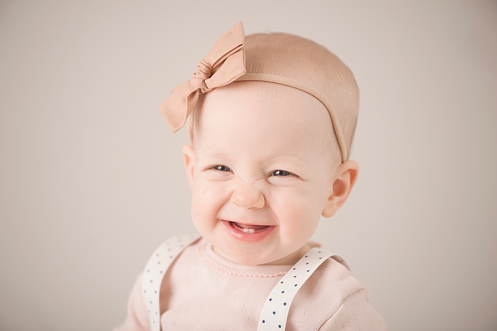 Smiling baby girl wearing a peach bow | Photo by Jessica Lee Photography 