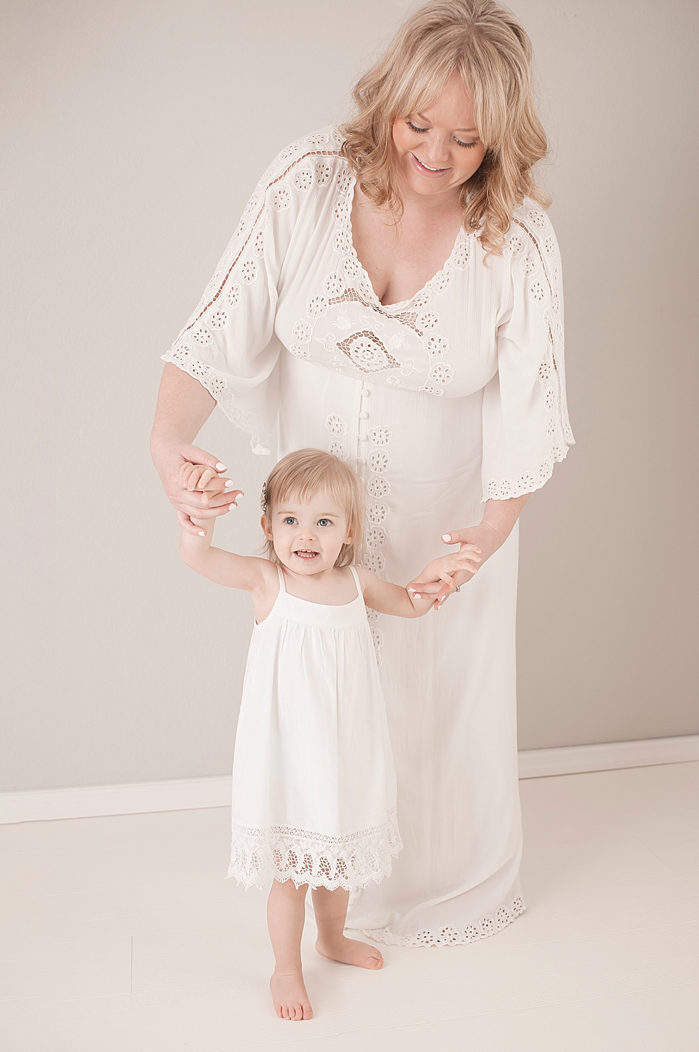 Mom holding hands with toddler girl in white dress | Photo by Jessica Lee Photography