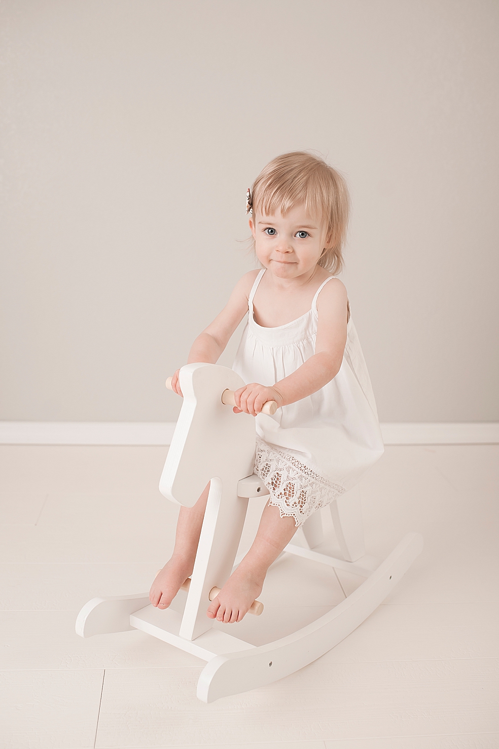Toddler girl in white dress on rocking horse | Photo by Jessica Lee Photography