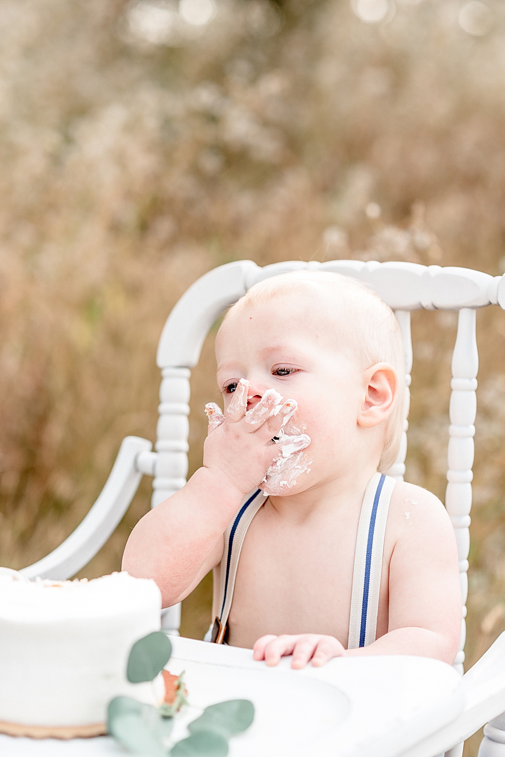 Baby boy eating cake in a white highchair | Photo by Jessica Lee Photography 
