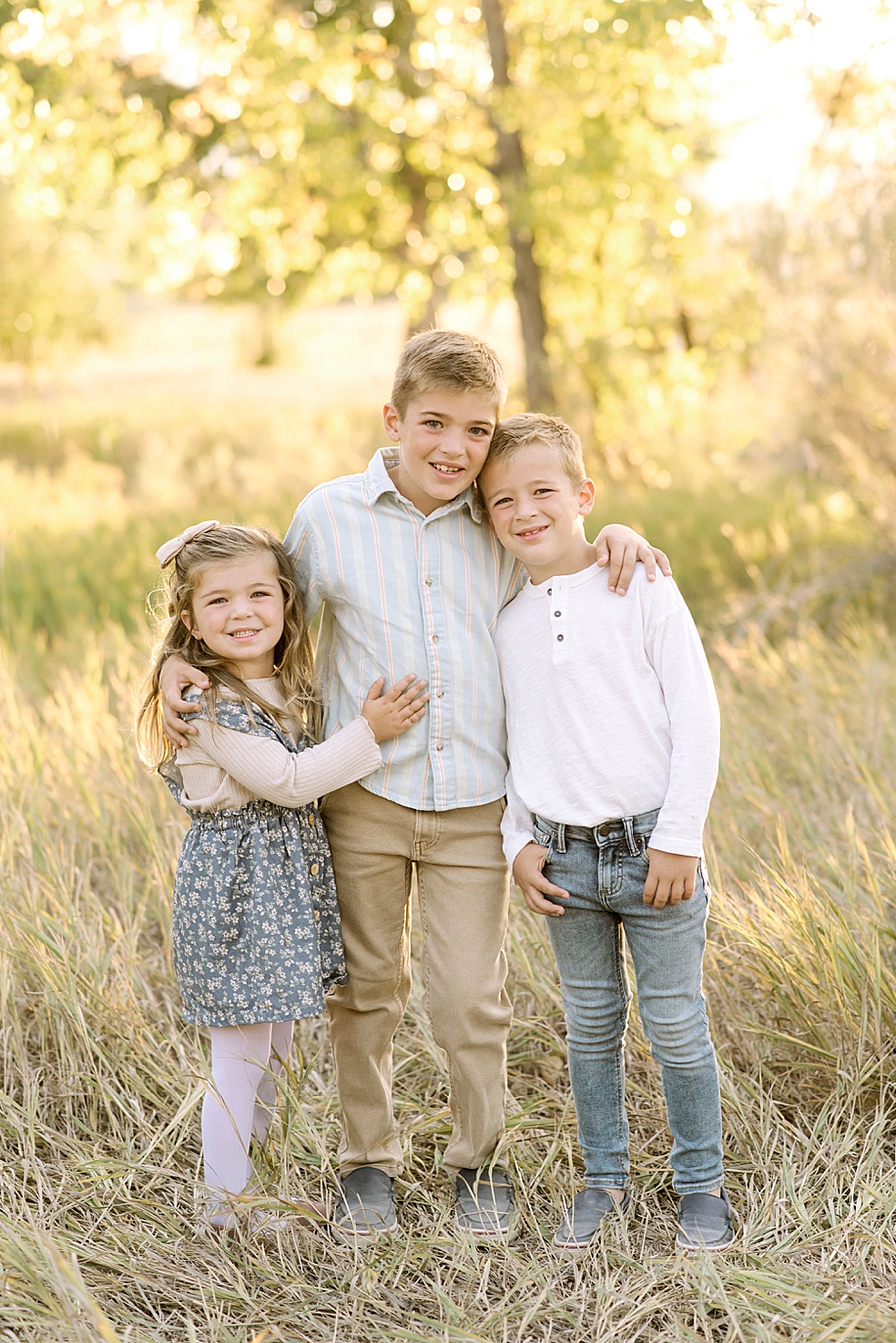 Siblings standing together in a field with golden light | Photo by Madison Alabama Family Photographer Jessica Lee