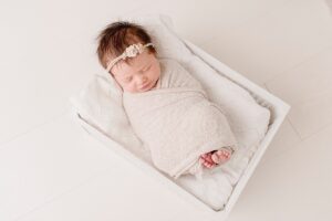 Newborn baby girl wrapped in white swaddle | Photo by Jessica Lee Photography