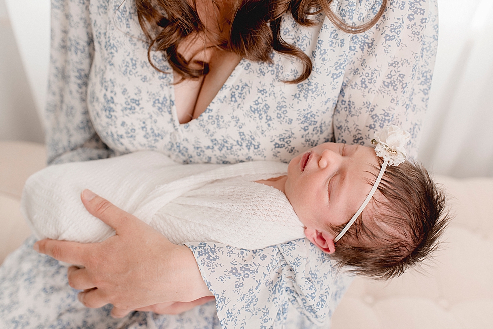 Sleeping newborn baby girl with headband held by mom | Photo by Jessica Lee Photography 
