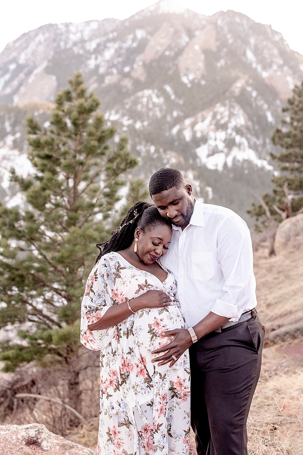Mom and dad to be snuggling in front of snow covered mountains | Photo by Jessica Lee Photography