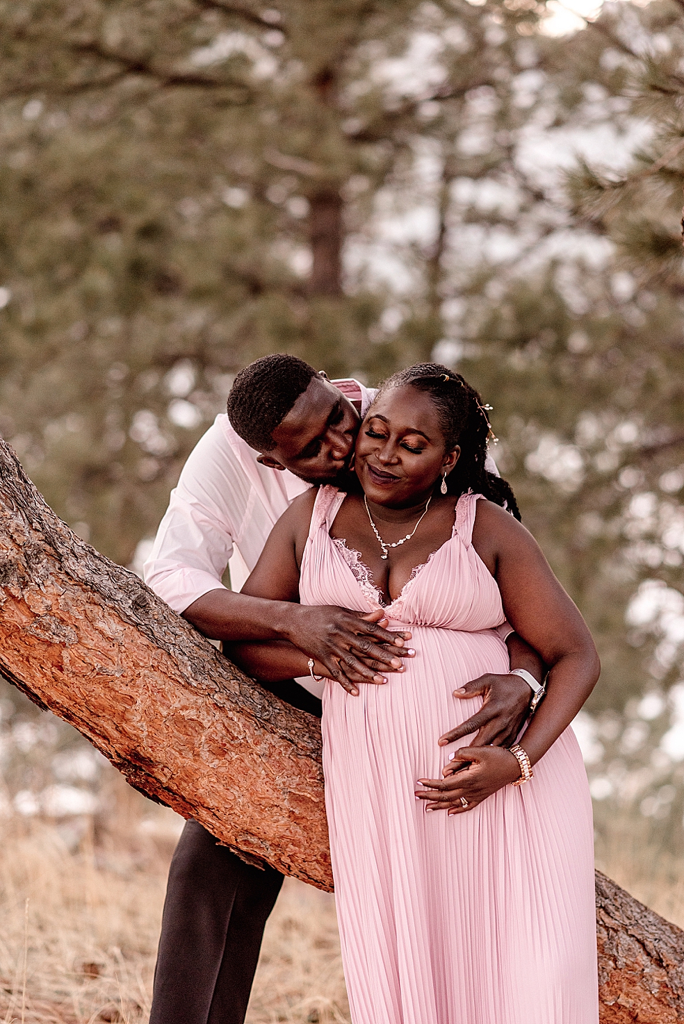 Dad kissing mom to be in a pink dress | Photo by Jessica Lee Photography