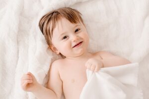 Toddle baby laughing under white blanket | Photo by Jessica Lee Photography
