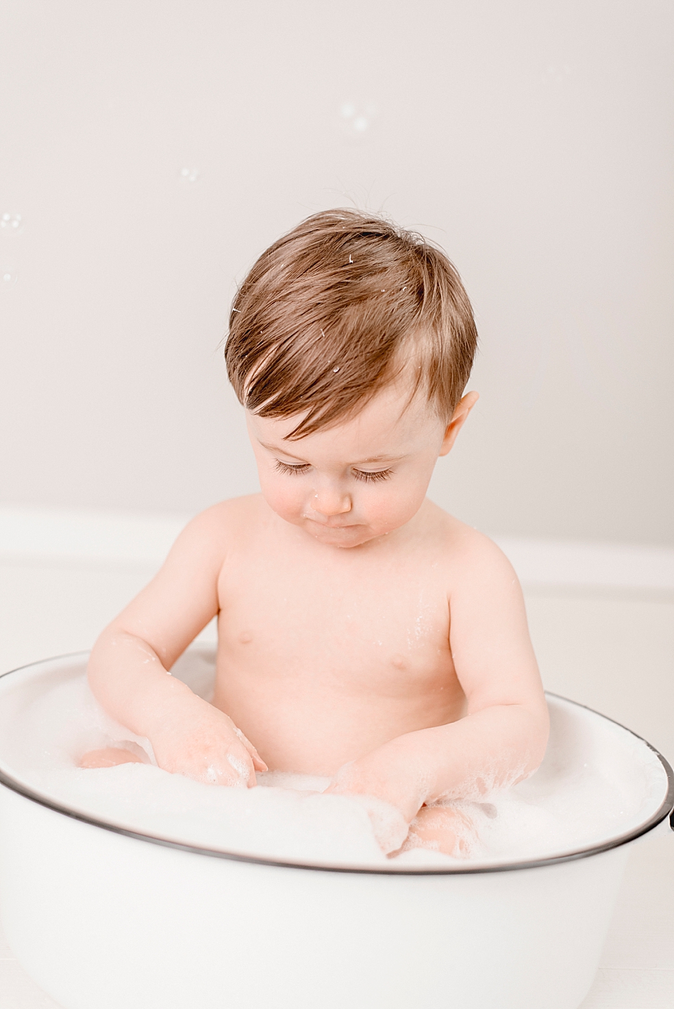 Baby boy in a tub playing with bubbles | Photo by Jessica Lee Photography