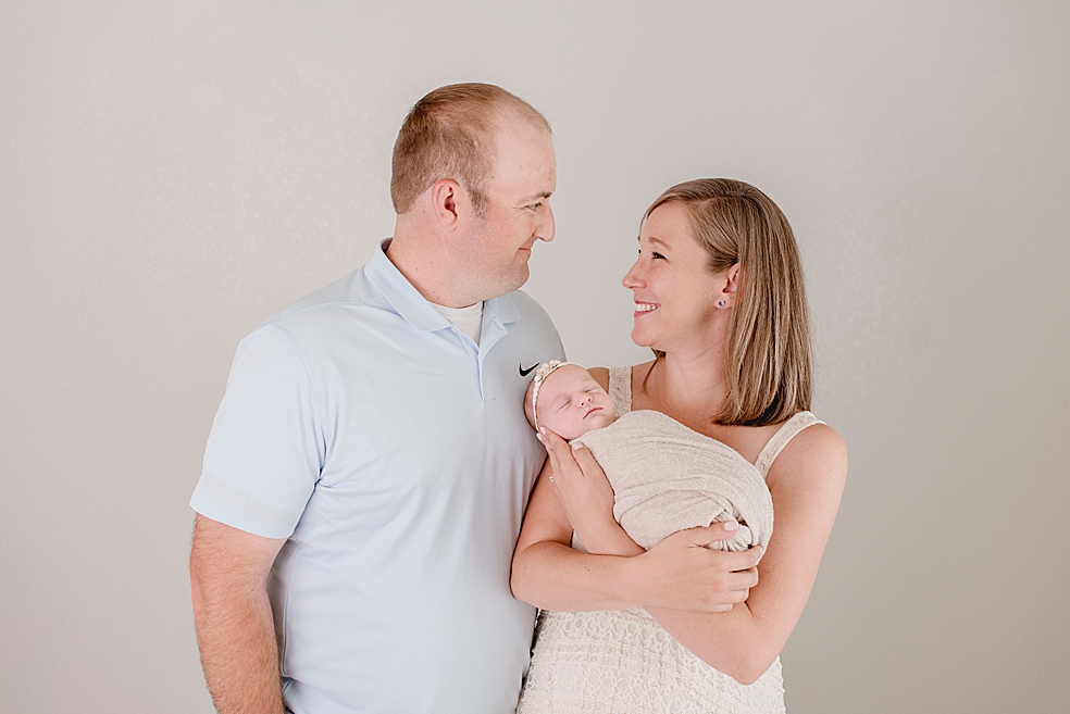 Mom and dad smiling while holding their newborn baby girl | Photo by Meridianville Newborn Photographer Jessica Lee