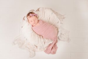 Newborn baby girl in a pink swaddle | Photo by Jessica Lee Photography