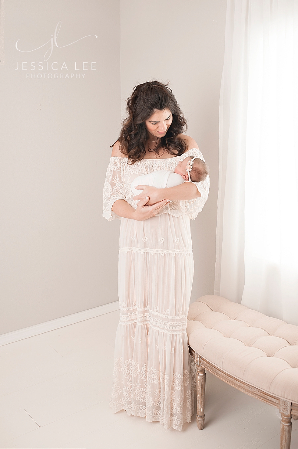New mom in a long white lace dress holding her baby | Photo by Jessica Lee Photography