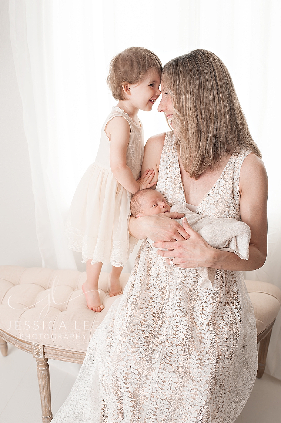Mom in a long white dress holding her babies | Photo by Jessica Lee Photography
