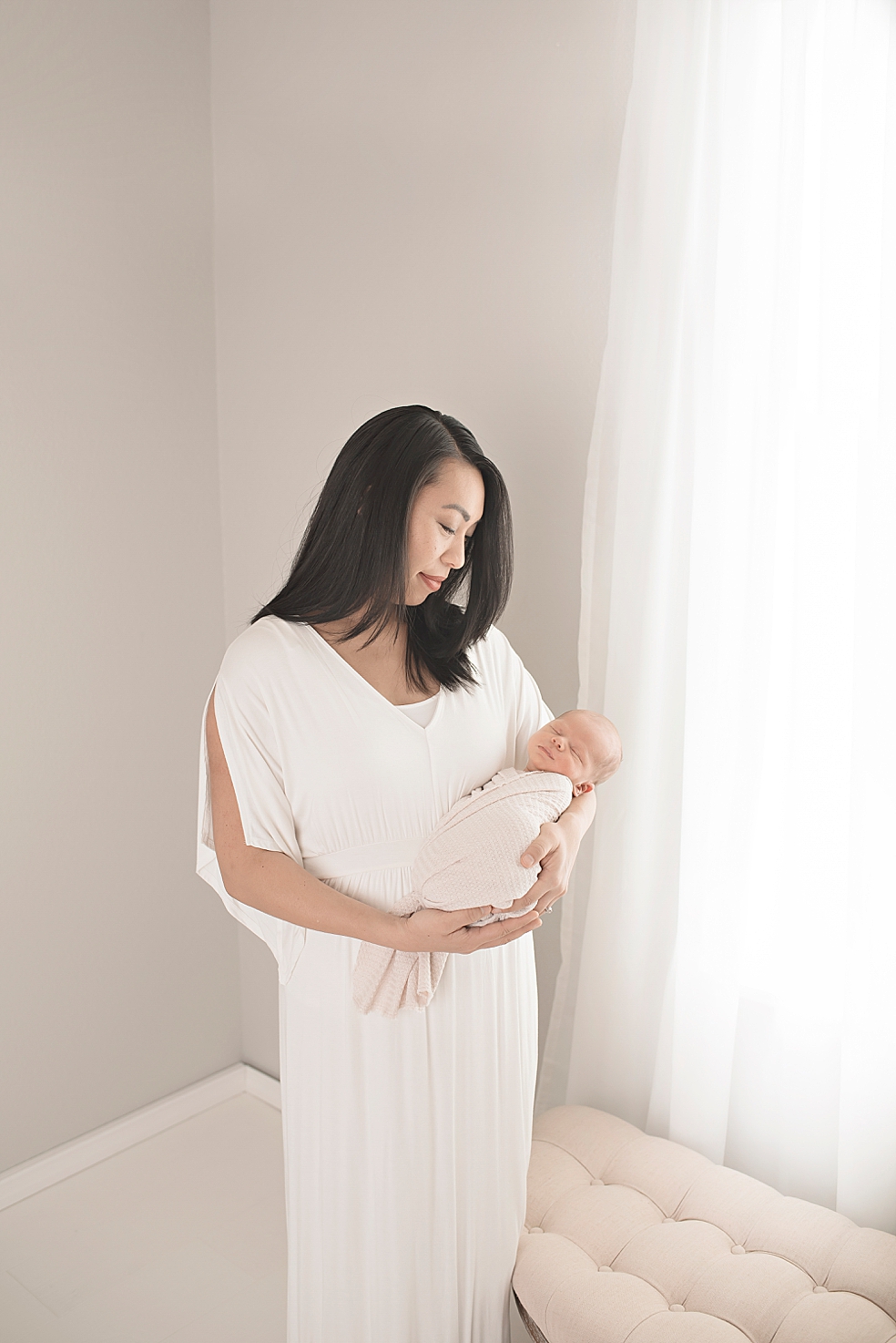 Mom in a long white dress holding her baby | Photo by Jessica Lee Photography