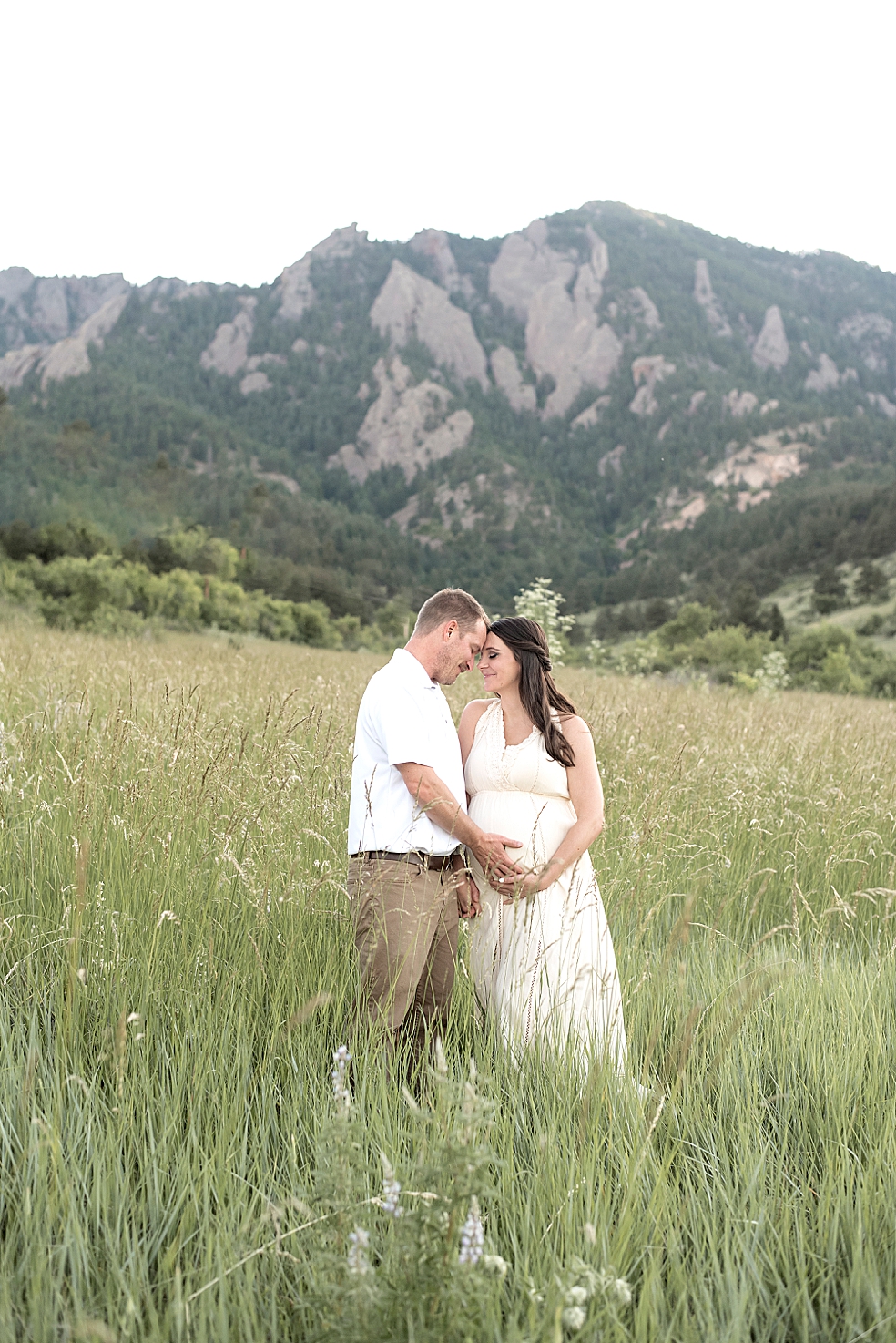 Mom and dad to be in a field snuggling | Photo by Jessica Lee Photography