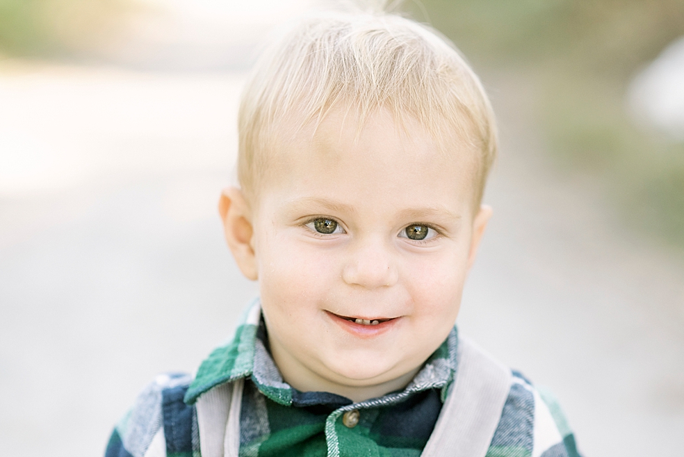 Little boy wearing plaid and overalls smiling | Photo by Jessica Lee Photography