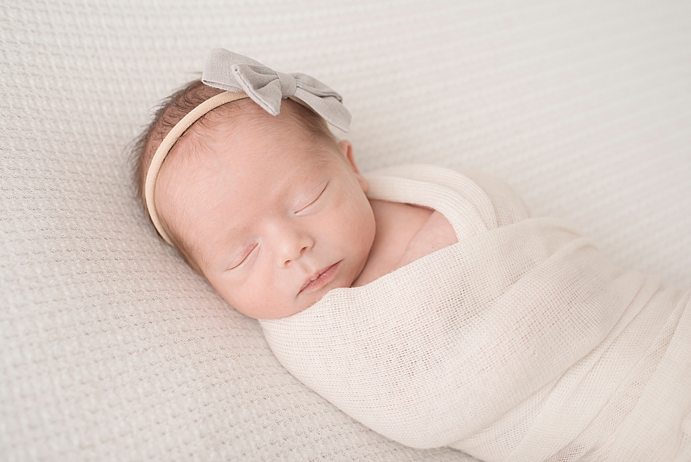 Baby girl wrapped in a cream swaddle | Photo by In-Home Huntsville Newborn Photographer Jessica Lee 
