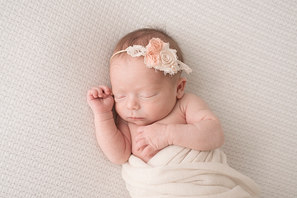 Baby girl with a headband wrapped in a white swaddle | Photo by In-Home Huntsville Newborn Photographer Jessica Lee 
