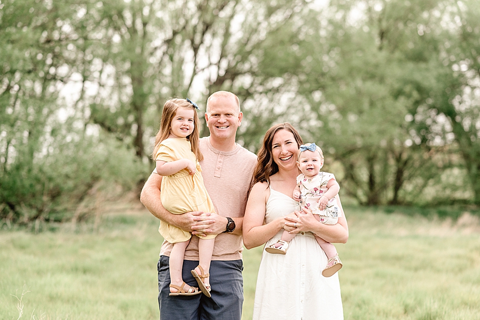Family of four smiling in a field | Photo by Light and Airy Alabama Photographer Jessica Lee 