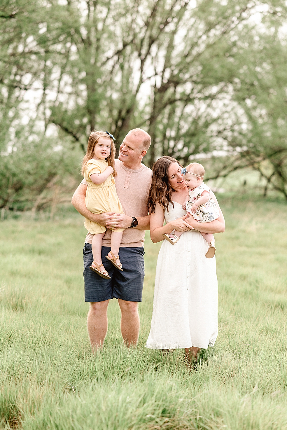 Family of four snuggling in a field | Photo by Light and Airy Alabama Photographer Jessica Lee 