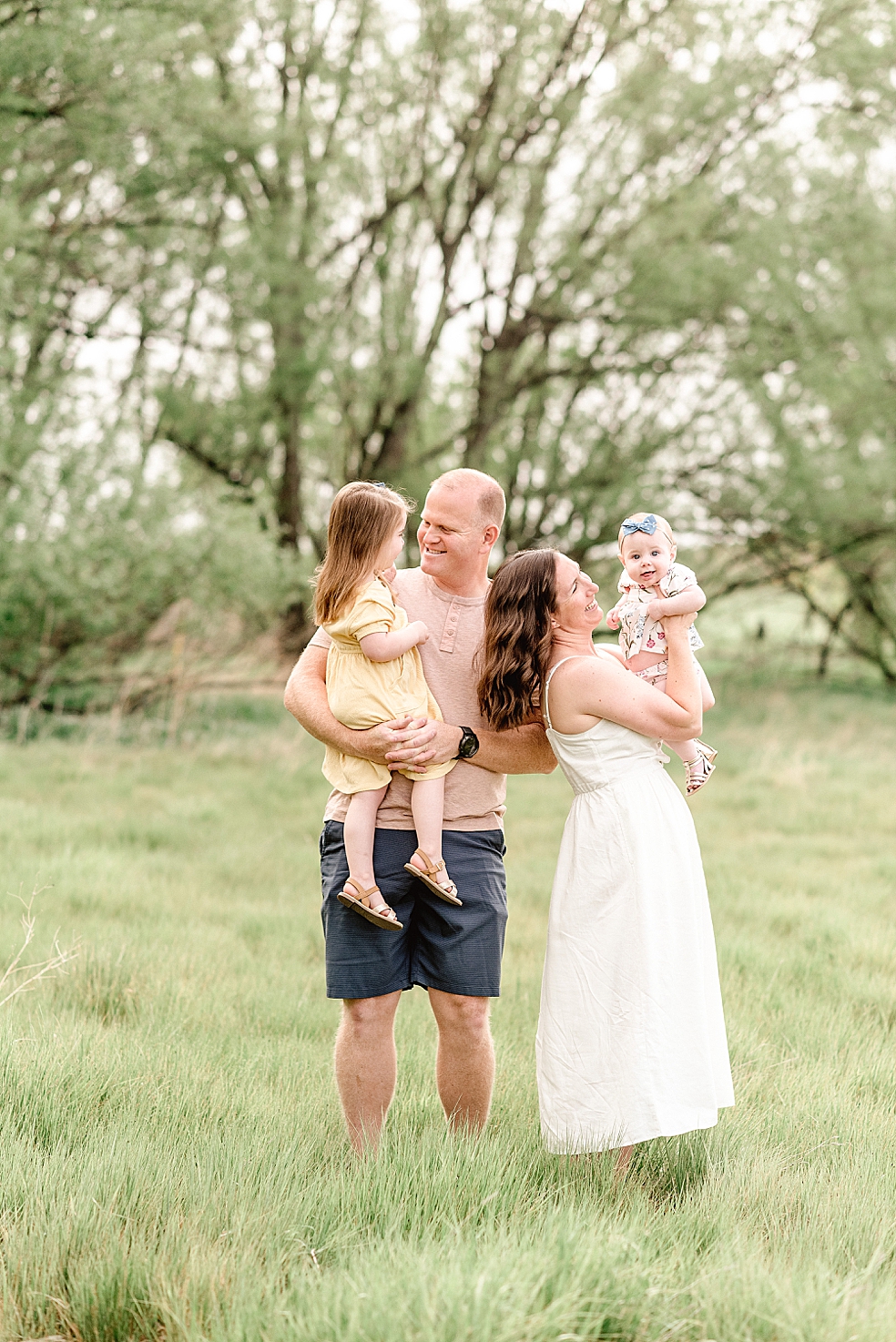 Mom and dad playing with their girls in a field | Photo by Light and Airy Alabama Photographer Jessica Lee 