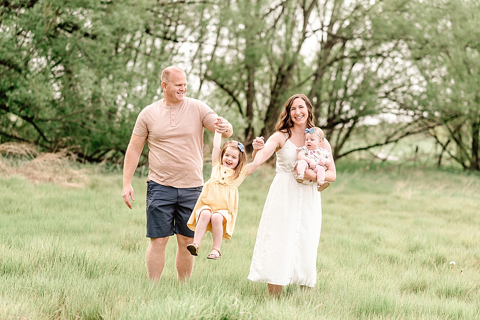 Mom and dad swinging their girls in a field | Photo by Light and Airy Alabama Photographer Jessica Lee 