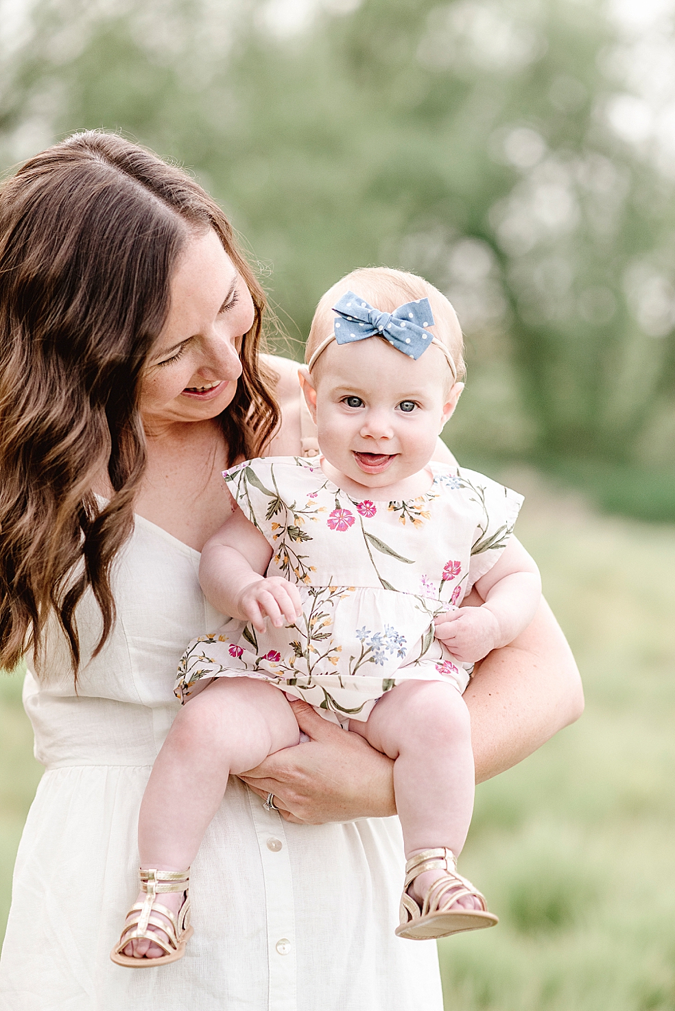 Mom holding her baby girl with a blue headband and floral print dress | Photo by Jessica Lee Photography