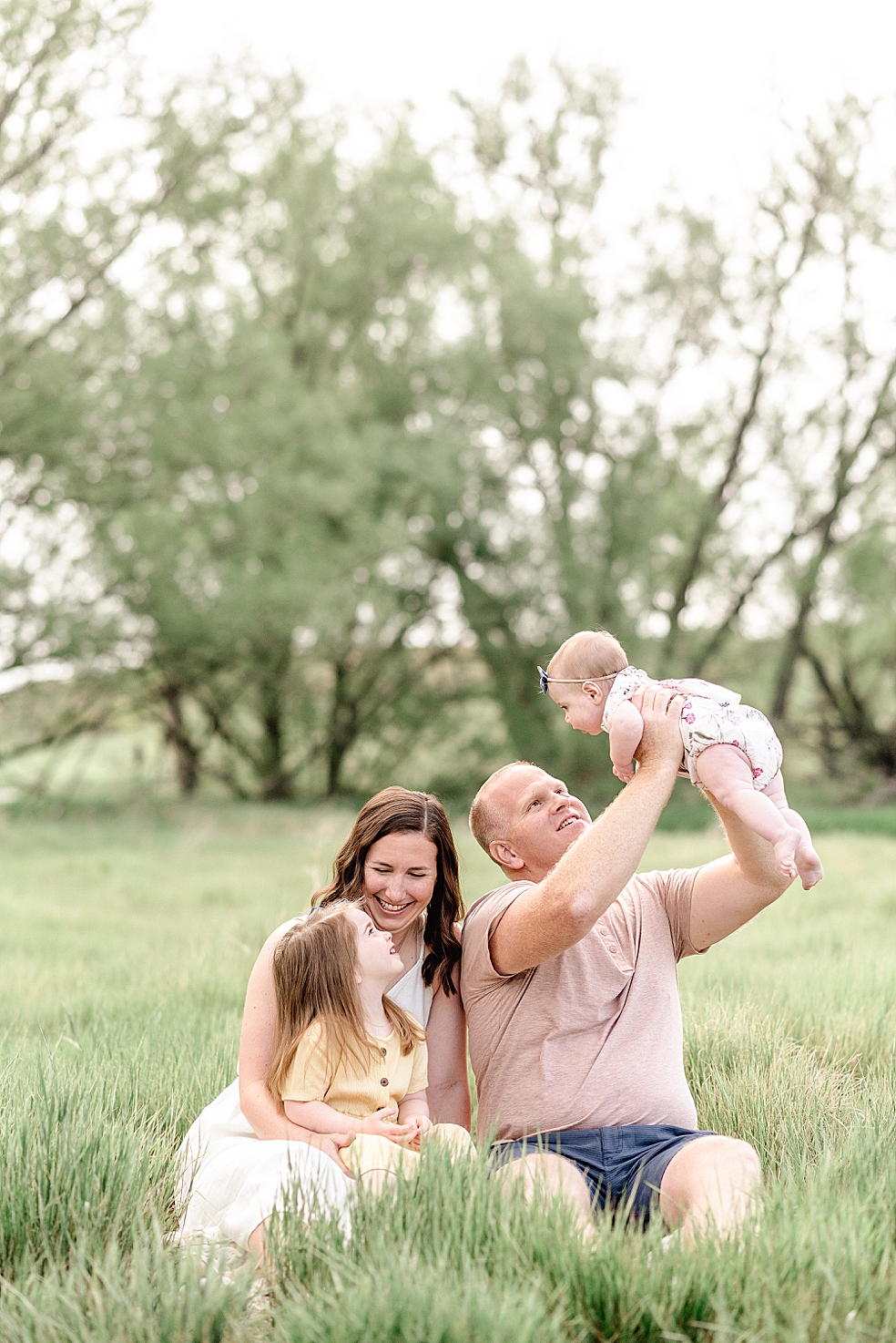 Mom and dad sitting in the grass with their girls | Photo by Jessica Lee Photography