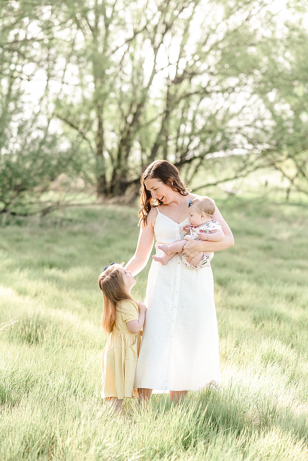 Mom playing with her two daughters in a field | Photo by Jessica Lee Photography