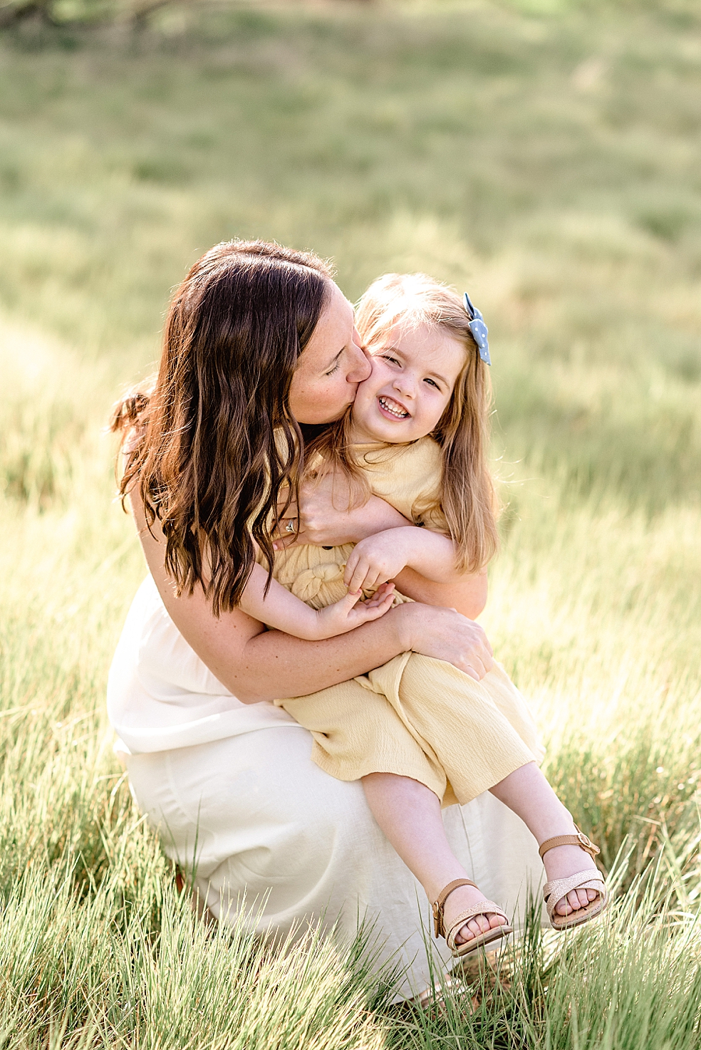 Mom kissing her toddler daughter in yellow | Photo by Jessica Lee Photography