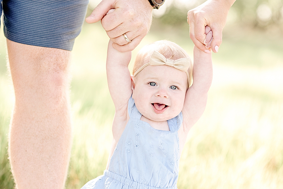 Baby girl held by mom and dad in a field | Photo by Jessica Lee Photography