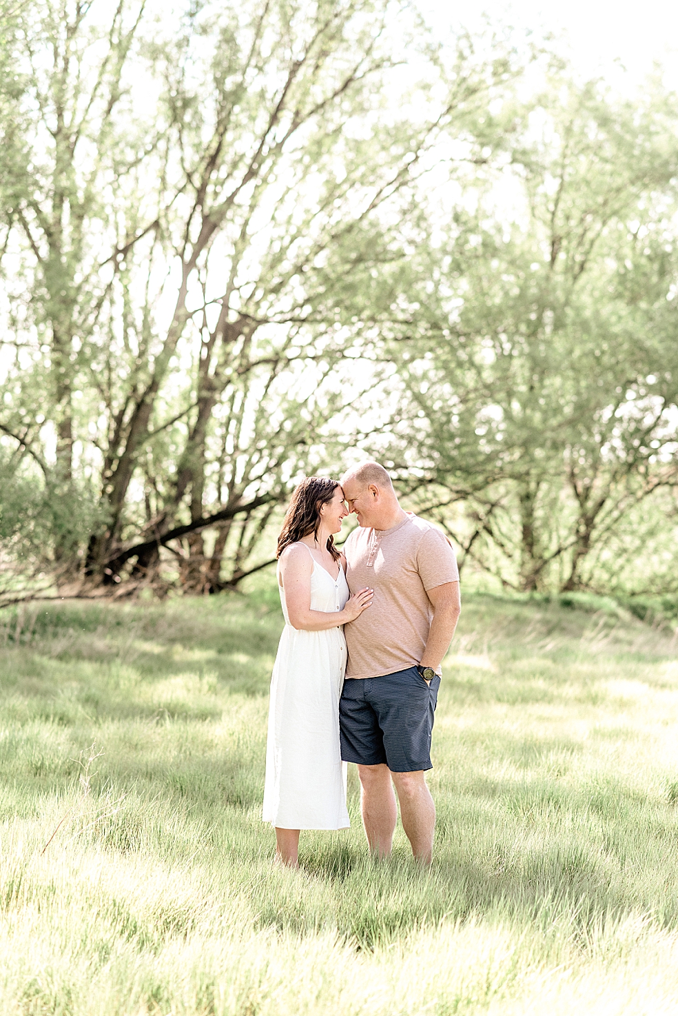 Mom and dad snuggling in a field | Photo by Light and Airy Alabama Photographer Jessica Lee 