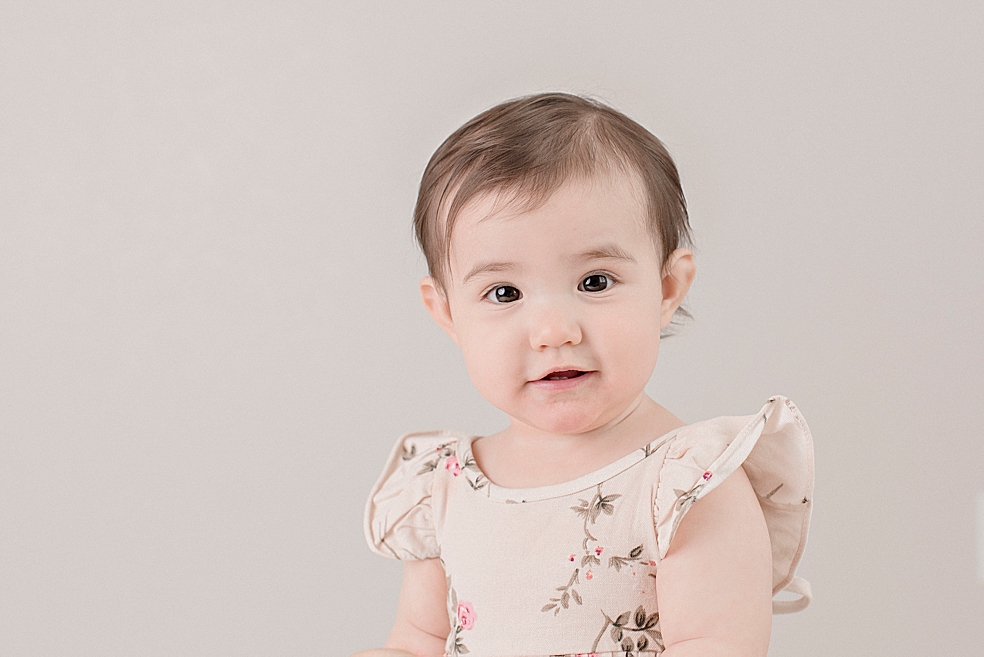 Baby girl in a floral dress smiling | Photo by Jessica Lee Photography